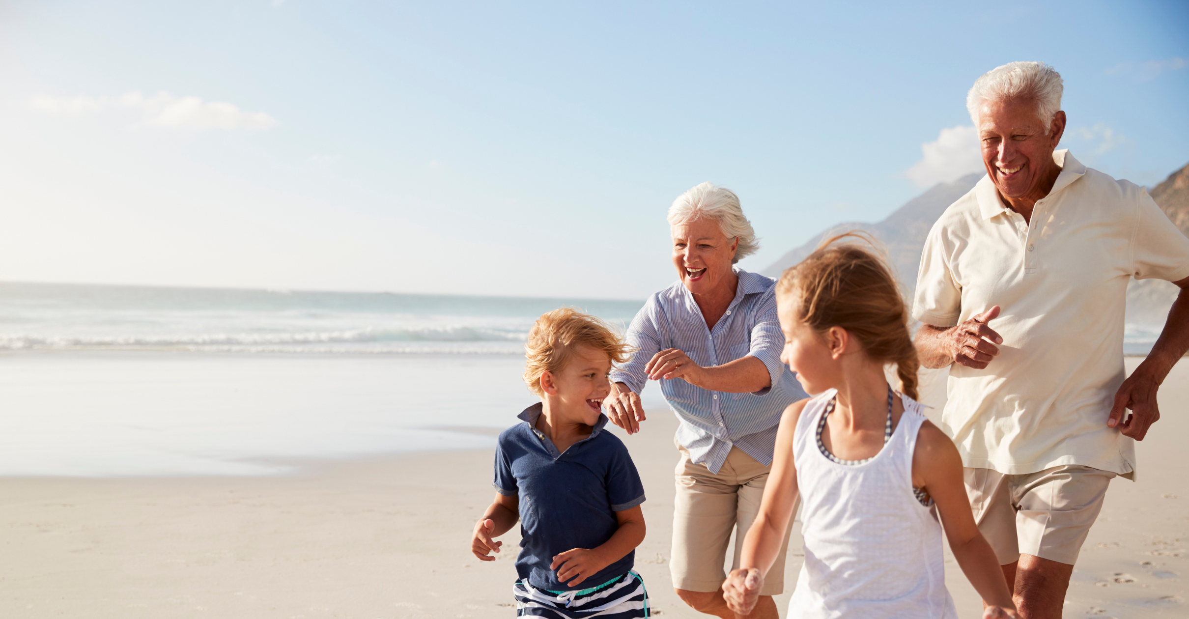 Grandparents running along the beach with their grandchildren
